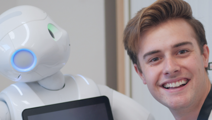 On the left, a Pepper robot looks up. On the right, a man smiles to the camera.