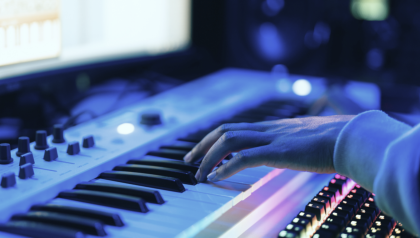 In the picture, you can see a hand playing piano. The instrument is connected to a computer.