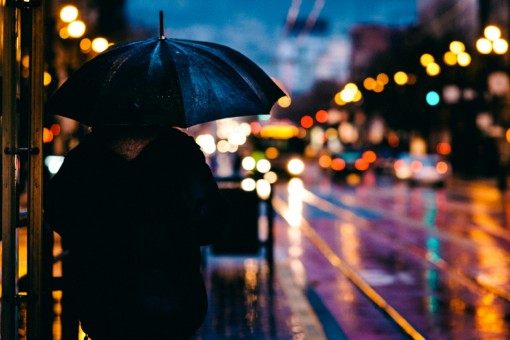 A person walking alone in the rain with an umbrella.
