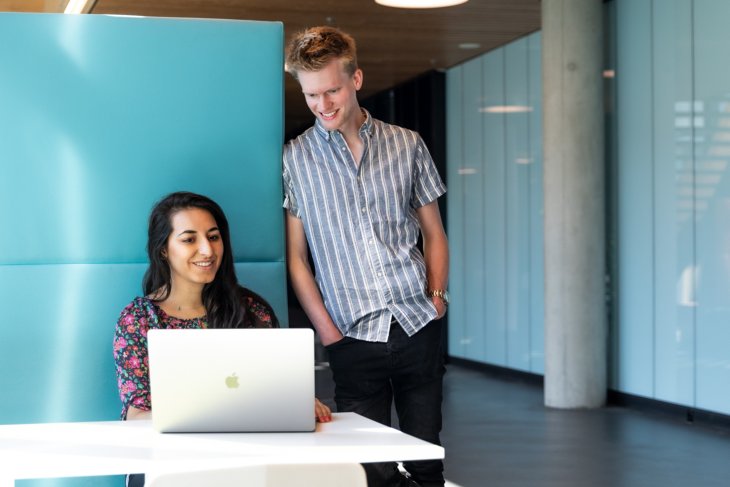 Twee studenten kijken samen op een laptop.
