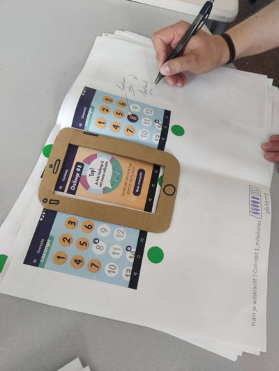 Participant writes suggestions with a pen on a paper prototype of an app