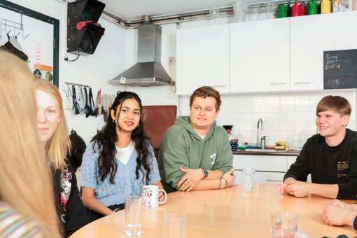 Students sitting at a table in their kitchen talking.