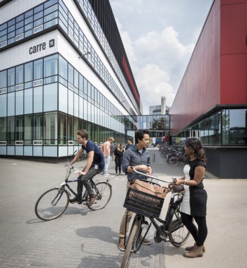 Studenten fietsen en kletsen op de campus van de Universiteit Twente.