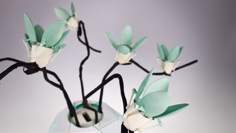 A blue and green robotic plant glows with a smartphone leaning against it