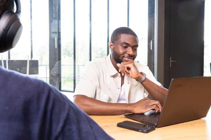 A student is sitting behind his laptop, looking at the screen.
