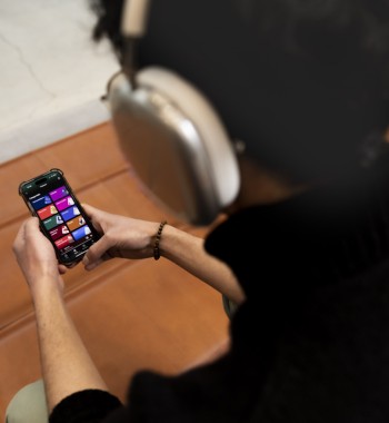 Een student van de Universiteit Twente kiest een podcast uit op basis van zijn studie. Je ziet zijn achterhoofd met koptelefoon en de Spotify app op zijn telefoon.