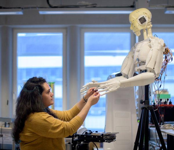 Girl touching the hands of a robot