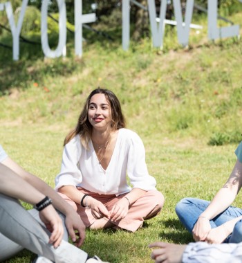 Vier studenten die kletsen in het gras op een zonnige dag.
