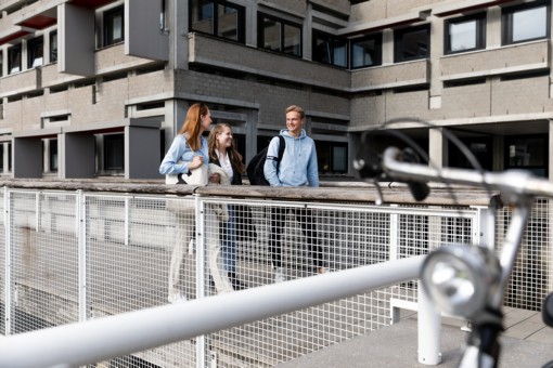 Three students walking on campus talking.