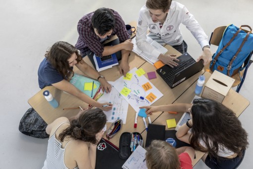 Studenten werken samen aan een groepsproject met notities, laptop en schrijfgerei.