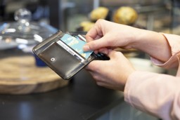 A student opens her wallet to pay by card.