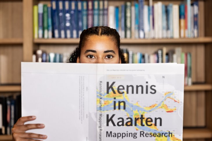 Student holding a book and looking in the camera