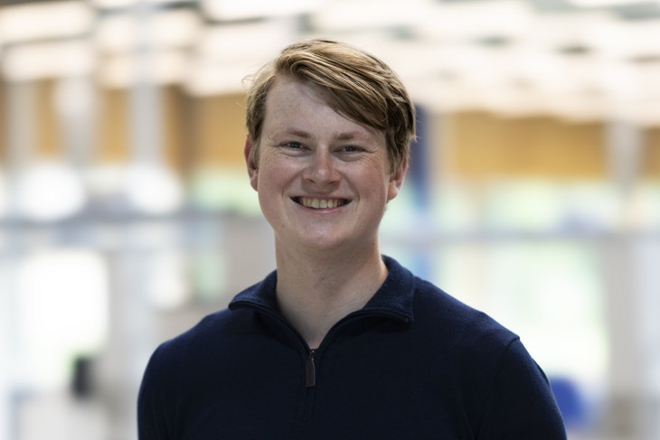 Student Computer Science Michael lacht in de camera in een werplaats op de campus van de Universiteit Twente.