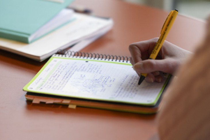 A University of Twente student taking notes in a notebook.