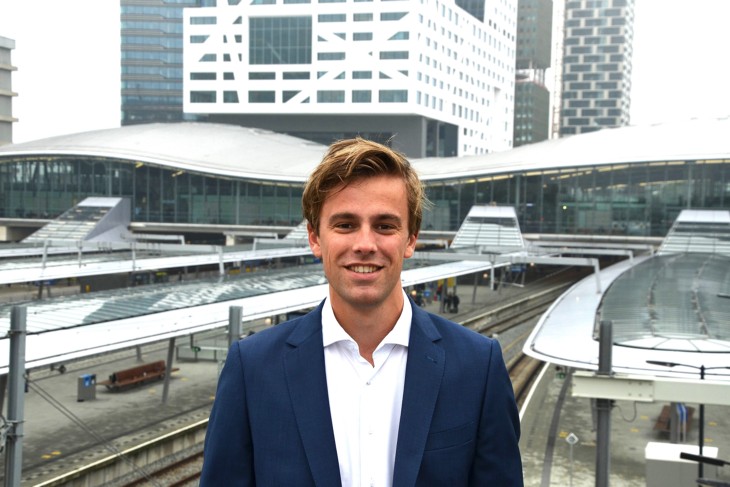 Construction Management & Engineering alumnus Robin from the University of Twente smiles into the camera, standing in front of a station.
