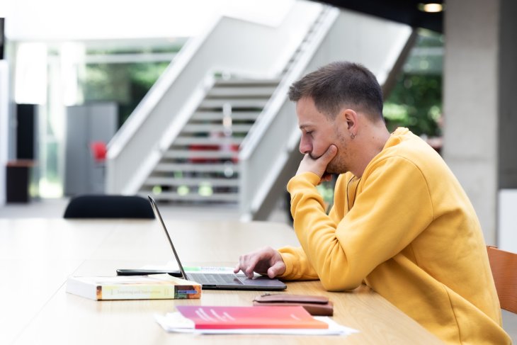 Een student studeert achter zijn laptop.