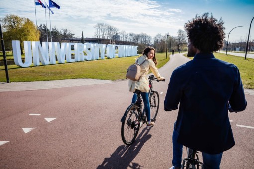 Students biking in front of the entrance of the UT campus