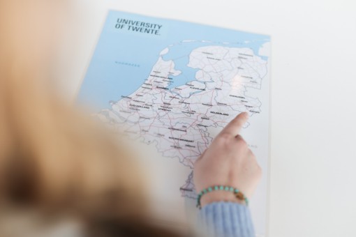 Student pointing at the University of Twente on a map of the Netherlands
