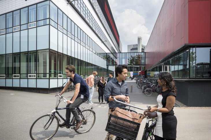 Studenten fietsen en kletsen op de campus van de Universiteit Twente.
