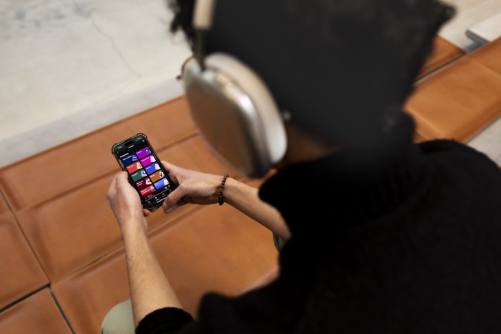 Een student van de Universiteit Twente kiest een podcast uit op basis van zijn studie. Je ziet zijn achterhoofd met koptelefoon en de Spotify app op zijn telefoon.