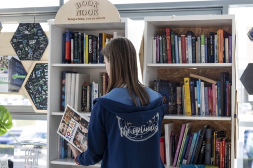 A student grabs a non-fiction book from a bookcase.