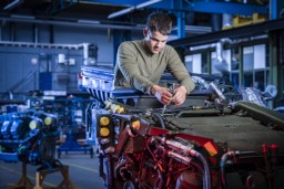 Technician performing maintenance on a defense vehicle in a workshop, smart maintenance for military applications