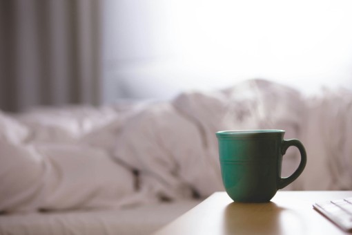 A cup of coffee on a bedside table.