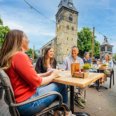 Terras in Enschede met mensen en Grote Kerk op de achtergrond.