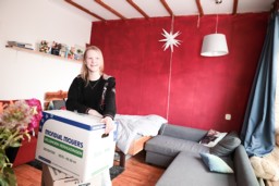 Een student staat in haar kamer met een verhuisdoos.