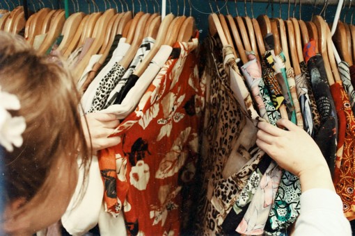 Someone looking through a row of vintage clothing.