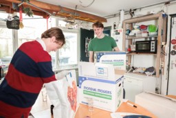 Twee studenten met verhuisdozen op de keukentafel in een studentenhuis.