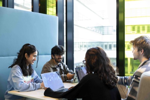 Four students sit around a table working on a group project.