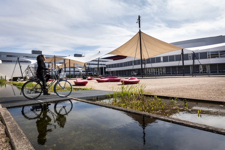 Een student fietst op het O&O Plein op de campus.