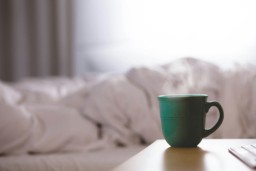 A cup of coffee on a bedside table.