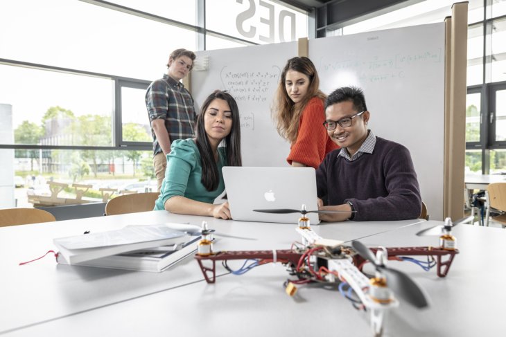 Four students study a drone
