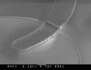 Figure 1: microchannel made by sacrificial KOH-etching of poly-Si, crossing a channel made by anisotropic KOH-etching of the mono-crystalline substrate.  b) Close-up near the entrance of the microchannel