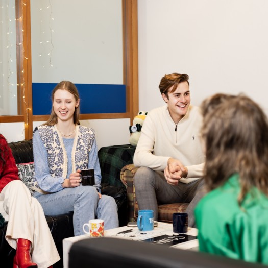 Een groep studenten lacht en praat op de campus.